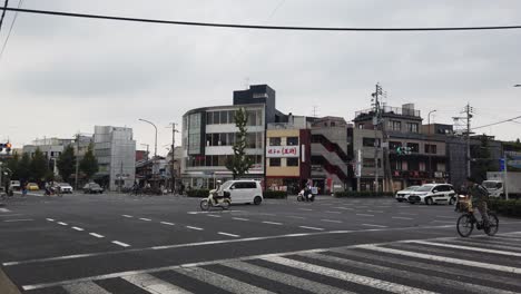 Static-Shot-in-Kyoto-City-Streets-Junction,-Car-Road-Traffic,-Driving-Bicycles-and-Pedestrians,-Japanese-City,-Japan
