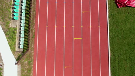 Aerial-top-down-shot-of-empty-running-track-and-empty-seats-of-stand-spectator-in-Stadium-at-sunny-day