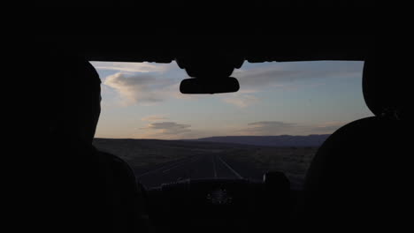 Silhouette-of-man-driving-down-the-desert-road-at-sunset-on-a-roadtrip