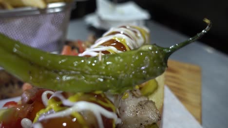 Slow-revealing-shot-of-a-hotdog-covered-with-different-sauces-and-a-jalapeno
