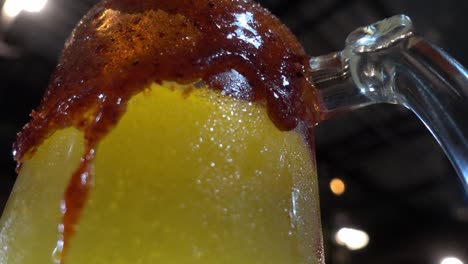 Slow-rotating-shot-of-an-orange-fizzy-drink-in-a-glass-with-sauces-rimmed-around-the-glass