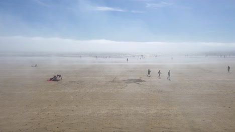 High-key-ethereal-fog-blows-over-people-on-sandy-ocean-beach,-Ireland