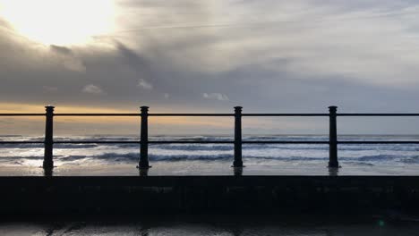 Morning-ocean-waves-crash,-splash-over-seawall-in-Tramore,-Ireland