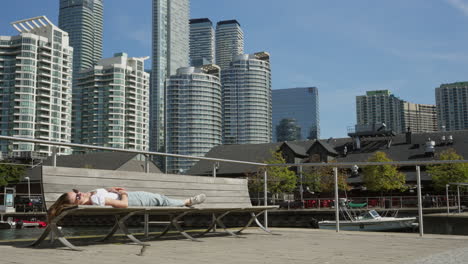 Lady-is-sleeping-on-a-bench-with-a-bird-in-Toronto