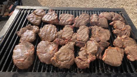 Eighteen-large-beef-steaks-cook-on-hot-outdoor-BBQ-rebar-grill