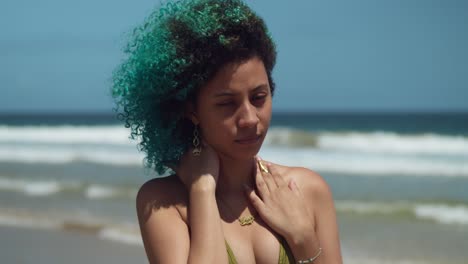 Pretty-girl-facial-close-up-on-a-beach-with-green-curly-hair-blowing-in-the-wind
