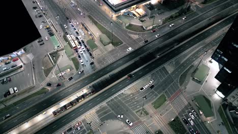 Aerial-drone-night-video-of-illuminated-Crossroad,-multi-lane-highway-through-urban-city-center-popular-multilevel-junction