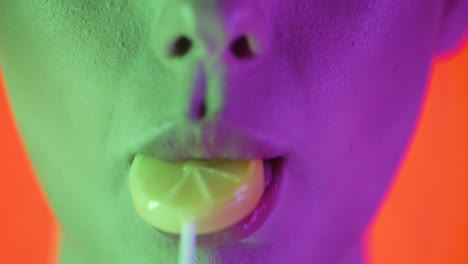 Close-up-shot-of-beautiful-full-sexy-lips-of-a-young-woman-licking-a-lick-sweet-lollipop-with-the-shape-of-a-lemon-and-letting-her-tongue-roam-over-the-lips-in-slow-motion