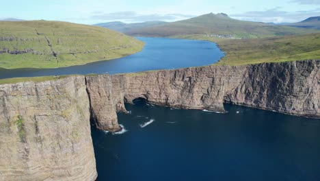 Aerial-shot-of-Lake-Sorvagsvatn-meander-and-Traelanipa-cliff-with-hikers-on-its-edge