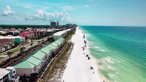 Drone-shot-flying-down-the-white-sand-beach-of-Destin-Florida-with-a-view-of-the-Gulf-of-Mexico-on-the-right-and-some-beautiful-houses-and-condos-on-the-left