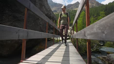 Low-angle:-Man-on-wooden-bridge-with-mountain-backdrop