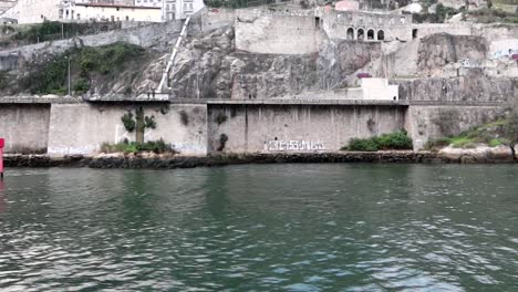 Muralha-Fernandina-old-walls-seen-from-moving-boat-over-Douro-River,-Porto