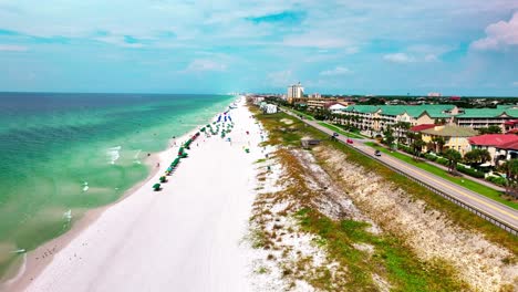 Drone-shot-flying-down-the-white-sand-beach-of-Destin-Florida-with-a-view-of-the-Gulf-of-Mexico-on-the-left-and-sea-oats-and-old-highway-98-on-the-right