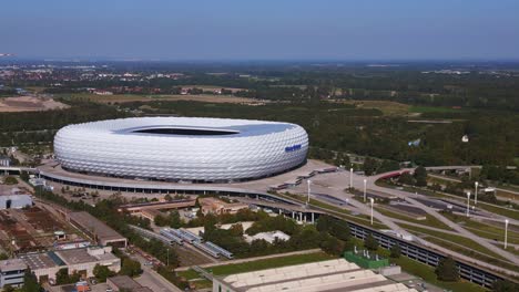 Fabulous-aerial-top-view-flight-Bavarian-Munich-Arena-stadium-national-football-soccer-team-Germany,-summer-sunny-blue-sky-day-23