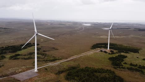 Drone-shot-circling-a-pair-of-wind-turbines-near-Stornoway,-Western-Isles