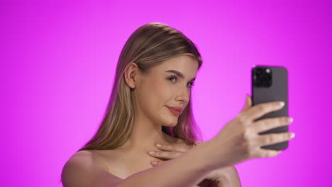 Medium-shot-of-a-young-pretty-influencer-or-model-live-streaming-on-social-media-sticking-her-tongue-out-to-her-followers-in-front-of-purple-background-in-slow-motion