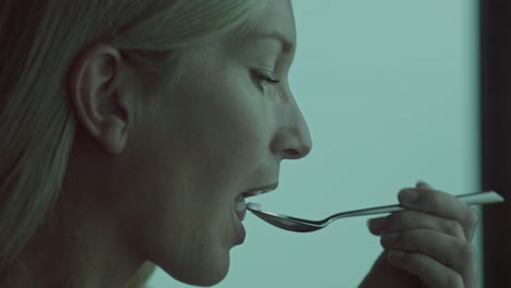 Close-up-of-attractive-woman-tasting-food-from-spoon-with-joyful-expression