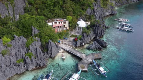 Traditional-Tour-Boats-docked-at-an-abandoned-Religious-Shrine-on-Matinloc-Island,-hidden-among-jagged-Karst-rock-outcrops