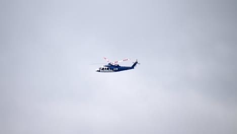 Helicóptero-Volando-En-Tiempo-Real-Con-Una-Pista-De-Fondo-De-Cielo-Nublado