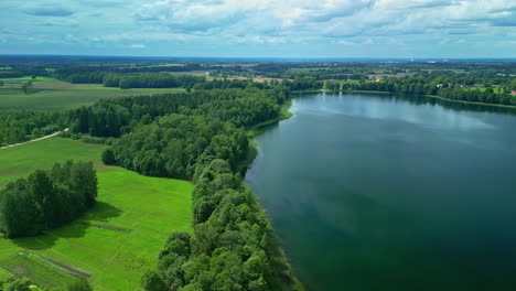 Bird's-eye-view-over-a-large-lake-between-green-meadows-and-trees