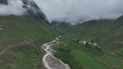 Accending-and-then-follow-drone-shot-over-the-calming-lake-and-lush-green-valley-in-Northern-area-of-Pakistan-on-a-cloudy-day