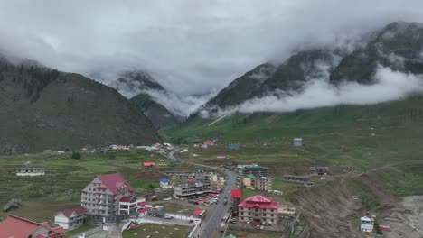 Follow-shot-of-drone-over-the-houses-and-road-between-green-valley-in-Naran-Batakundi-in-northern-region-of-Pakistan-with-low-clouds