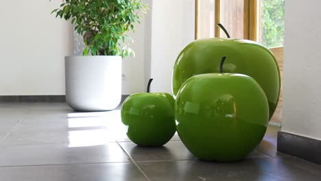 Decorative-object-of-green-apples-in-a-living-room,-with-a-window-in-the-background-and-a-plant