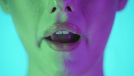 Extreme-close-up-of-beautiful-woman-lips-while-she-smiles-at-you-first-and-then-chews-a-gum-and-enjoys-the-taste-against-turquoise-background-in-slow-motion