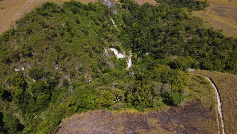 Aerial-Drone-View-Of-A-Waterfall-In-The-Midst-Of-Forested-Mountains-In-Sumba,-Indonesia