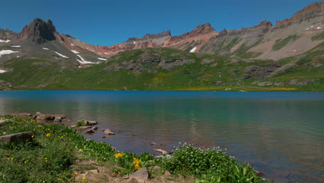Dreamy-heavenly-Silverton-Ice-Lake-Basin-aerial-drone-cinematic-unreal-deep-sky-blue-wildflower-shoreline-Silverton-Colorado-lush-green-summer-incredible-snow-melting-Rocky-Mountains-slider-right