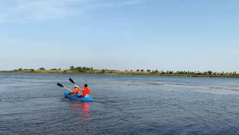 A-Couple-Enjoying-Kayaking-on-a-Tranquil-Waterscape-Beneath-Clear-Blue-Skies