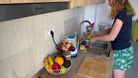 Frau-Wäscht-Einen-Apfel-über-Der-Spüle,-Um-Sicheres-Und-Sauberes-Essen-Zu-Hause-Zu-Gewährleisten