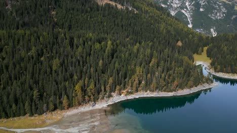 Drone-shot-of-the-Obernberger-Lake-lakeside-in-Austrias-Tyrol-with-very-clear-blue-water-and-reflections-of-the-mountains