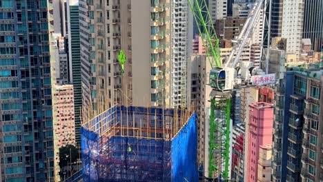 Turmdrehkran-Senkt-Holzbretter-Auf-Eine-Wolkenkratzerbaustelle-Im-Wohngebiet-Von-Hongkong