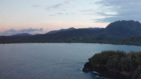 Wide-descending-aerial-shot-of-peaceful-Hanalei-Bay-from-the-Pacific-Ocean-during-low-light-on-the-island-of-Kaua'i,-Hawai'i