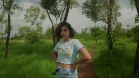 Middle-shot-of-an-Indian-colored-woman-in-a-lush-green-indian-forest-looking-confidently-directly-into-the-camera