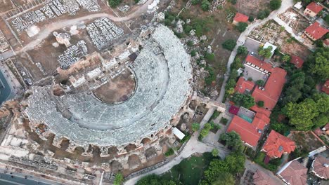 Aerial-view-looking-down-over-historical-Side-amphitheatre,-Turkey-and-traditional-old-town-residential-rooftops