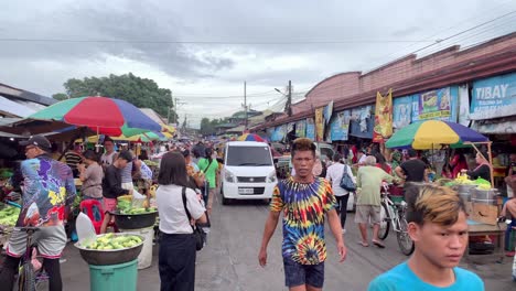 A-bustling-crowd-of-people-moves-steadily-along-the-street,-while-sellers-and-vendors-line-both-sides-of-the-road,-showcasing-their-wares