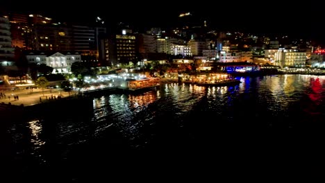 Saranda-Splendid-Night:-Illuminated-Promenade-Shimmers-on-the-Calm-Sea-Water,-Showcasing-the-Coastal-City's-Nocturnal-Beauty