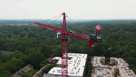 Orbit-shot-around-red-tower-crane-above-construction-site-of-modern-multistorey-building-in-urban-borough