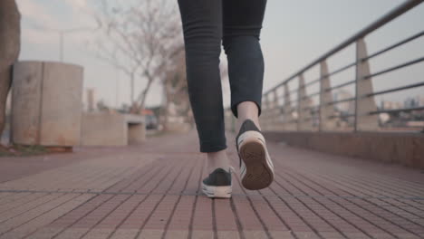 A-steady-close-up-shot-of-a-woman's-legs-and-feet-from-behind-as-she-walks-along-an-empty-path