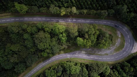 Vintage-Car-Navigating-a-Tight-Forest-Curve---Aerial-Top-shot-View