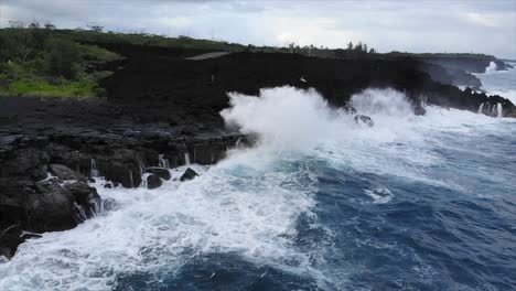 Rotating-view-of-waves-hitting-cliffs-from-ocean-perspective-showing-forest-and-volcanic-flow