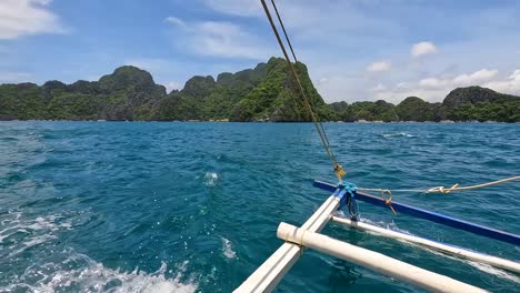 Scenic-landscape-view-of-outrigger-island-hopping-tour-boat-with-remote-tropical-islands-in-El-Nido,-Palawan,-Philippines