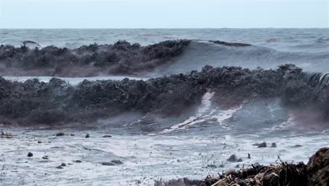 Muddy-ocean-waves-crash-onto-rocks