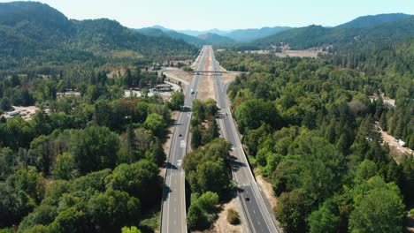 A-drone-flies-over-the-freeway,-cutting-through-the-mountains-and-trees-of-Oregon