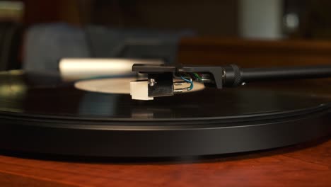 Close-up-view-of-a-moving-up-tonearm-of-a-turntable-with-platter-spinning,-slow-motion-4K