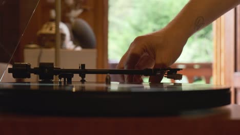 Low-angle-view-of-a-vintage-turntable-being-turned-on-and-spinning-by-a-person,-slow-motion-4K