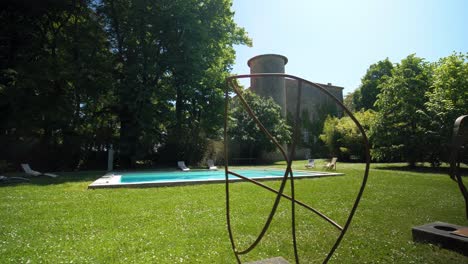 Stroll-in-the-Castle-Garden-with-Pool,-Metal-Artworks,-and-Castle-Tower-in-the-Background