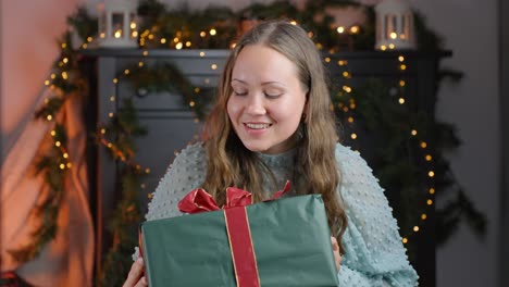 Woman-shaking-gift-box-guessing-what's-inside-while-smiling,-static-closeup